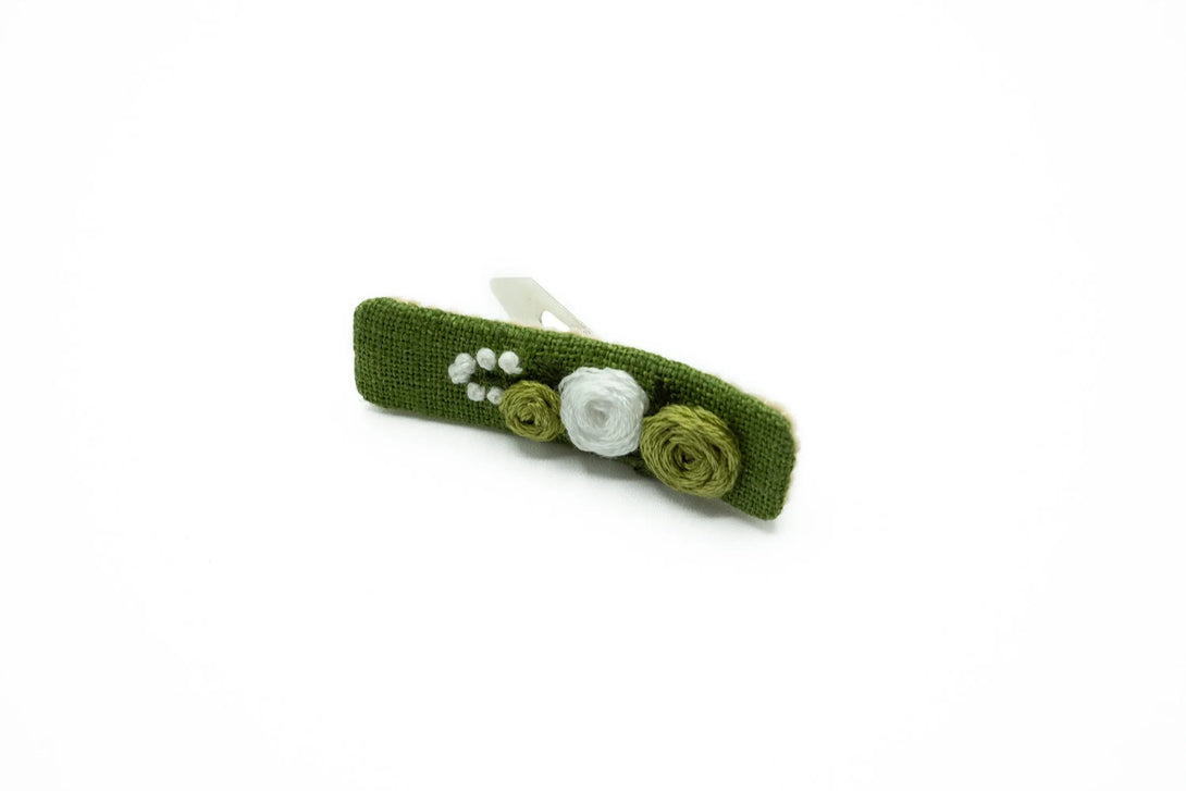 Close-up of a moss green floral hair clip, hand-embroidered with delicate white and green floral patterns, ideal for girls and women as a bridesmaid or baby shower gift