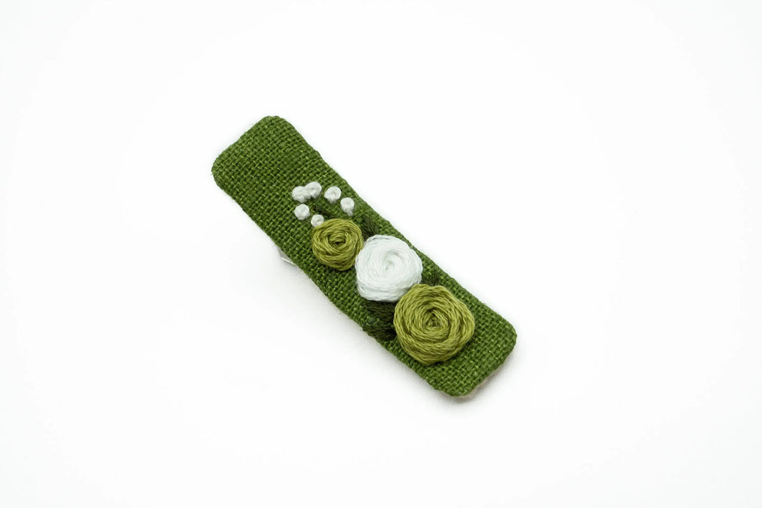 Detailed image of a handcrafted moss green floral hair clip, showcasing elegant white and green embroidered flowers, perfect for toddlers, girls, and women as a special occasion accessory